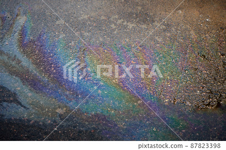 Oil stain on an asphalt road in a puddle in sunlight. 87823398
