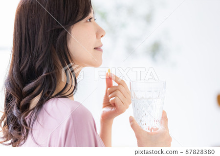 Female in a loungewear drinking capsule tablets Female in a loungewear drinking capsule tablets 87828380