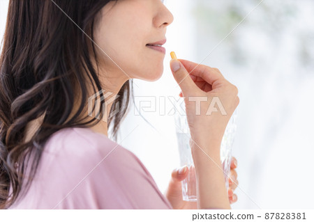 Female in a loungewear drinking capsule tablets Female in a loungewear drinking capsule tablets 87828381