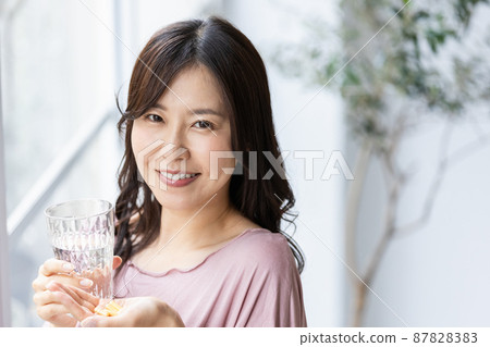 Female in a loungewear drinking capsule tablets Female in a loungewear drinking capsule tablets 87828383