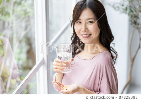 穿著休閒服的女性飲用膠囊片 87828385