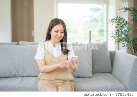 在沙發上使用智能手機的女人 在沙發上使用智能手機的女人 87832435