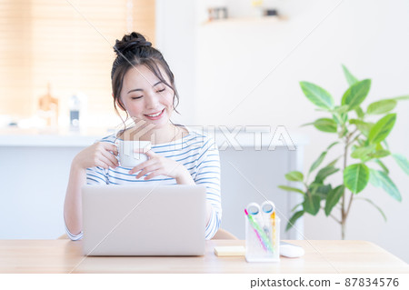 Young woman taking a break during telework in the living room Young woman taking a break during telework in the living room 87834576