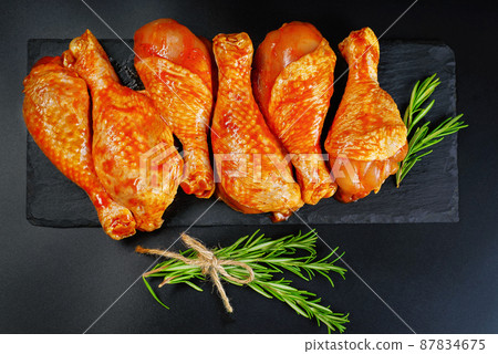 Convenience food, precooked.Raw Marinated chicken meat legs with spices for cooking for BBQ dark background. Top view.Copy space. 87834675