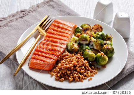 grilled salmon, brussel sprouts, spelt on a plate 87838336