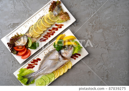 Fresh sea fish with lemon on plate Fresh sea fish with lemon on plate 87839275