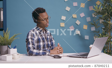 Helpline operator giving telemarketing assistance and support at client care call center, talking on phone call with people. Sales adviser using microphone and headphones at customer service. Helpline operator giving telemarketing assistance and support at client care call center, talking on phone call with people. Sales adviser using microphone and headphones at customer service. 87840211