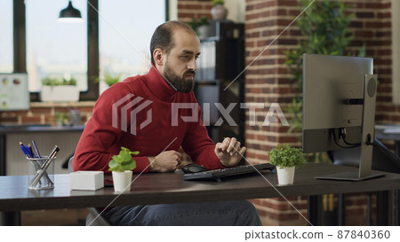 Satisfied businessman celebrating work achievement in office, feeling happy about good news and victory. Proud employee working on financial project and enjoying big growth success. 87840360