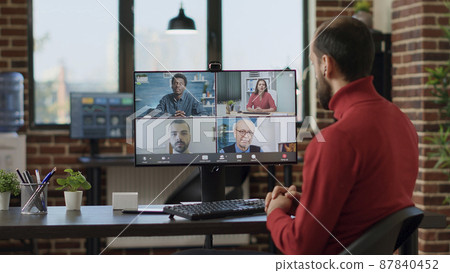 Businessman talking to colleagues on remote videoconference, meeting on online videocall communication with internet connection. Young adult using teleconference at office job. Tripod shot. 87840452