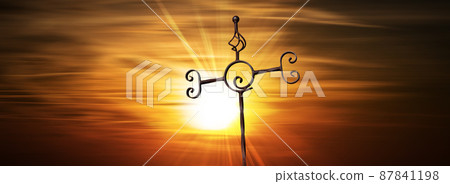 Wrought Iron Religious Cross on a Dramatic Sunset Sky with Sunbeams 87841198