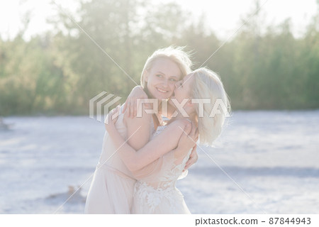 Beautiful lesbian couple walking on sand along river bank on their wedding day 87844943