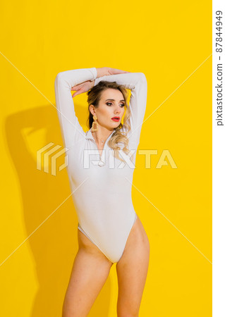 Young woman in white bodysuit posing on studio background. Female fashion, beauty and body concept Young woman in white bodysuit posing on studio background. Female fashion, beauty and body concept 87844949
