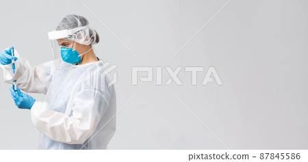 Covid-19, medical research, diagnosis, healthcare workers and quarantine concept. Doctor in personal protective equipment, holding coronavirus vaccine and put it in syringe, making shot patient Covid-19, medical research, diagnosis, healthcare workers and quarantine concept. Doctor in personal protective equipment, holding coronavirus vaccine and put it in syringe, making shot patient 87845586