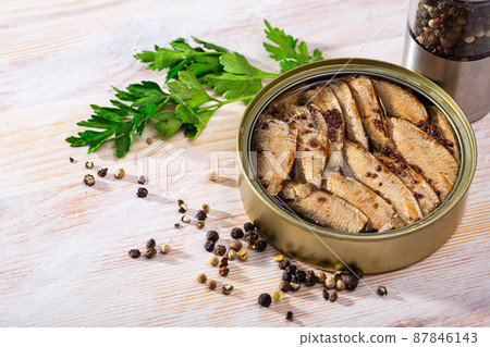 Tinned small smoked sardines on background with greens Tinned small smoked sardines on background with greens 87846143