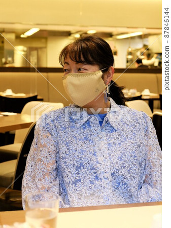 Female tourist in a handmade mask sitting in a hotel restaurant 87846144
