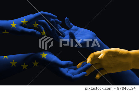 Painted in blue EU flag and blue-yellow colors of Ukrainian flag hands touching isolated on dark background. Concept of help, support Painted in blue EU flag and blue-yellow colors of Ukrainian flag hands touching isolated on dark background. Concept of help, support 87846154