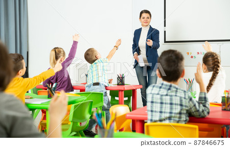 Smiling teacher examining pupils at lesson Smiling teacher examining pupils at lesson 87846675
