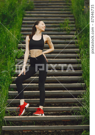 Woman in a black spoerswear standing on a stairs 87846735