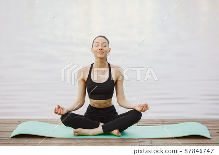 Woman practicing advanced yoga by the water 87846747
