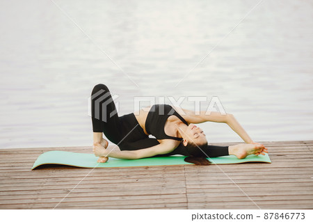 Woman practicing advanced yoga by the water Woman practicing advanced yoga by the water 87846773