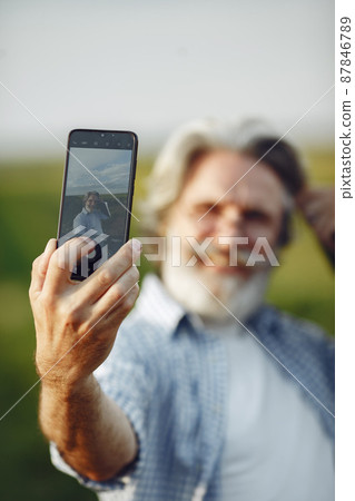 Old farmer in shirt standing on field with notebook 87846789
