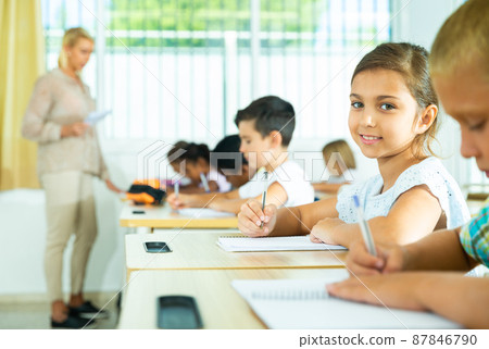 Side view of group of primary school students and positive girl at desk Side view of group of primary school students and positive girl at desk 87846790