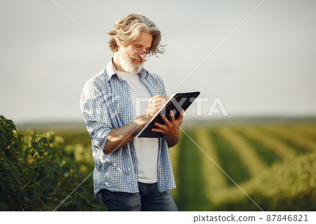 Old farmer in shirt standing on field with notebook Old farmer in shirt standing on field with notebook 87846821