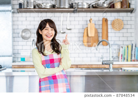 Young woman in a kitchen apron 87848534