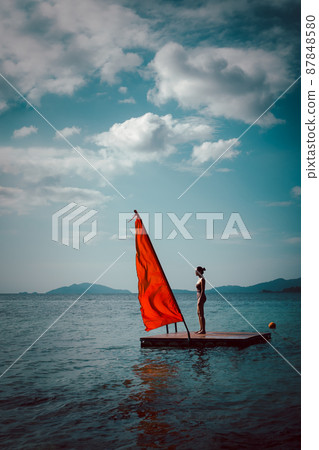 Beauty and fashion woman in swimming suit standing on wooden raft in the ocean. 87848580