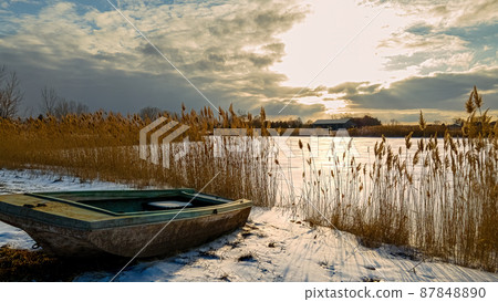 Heavenly winter clouds above a abandoned rural boat on lake 87848890