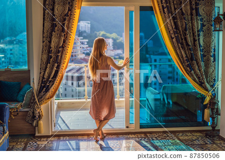 Woman on the balcony against the backdrop of mountains and city, Montenegro. life terrace pretty happiness summer home. Inspiration city romantic hotel Woman on the balcony against the backdrop of mountains and city, Montenegro. life terrace pretty happiness summer home. Inspiration city romantic hotel 87850506