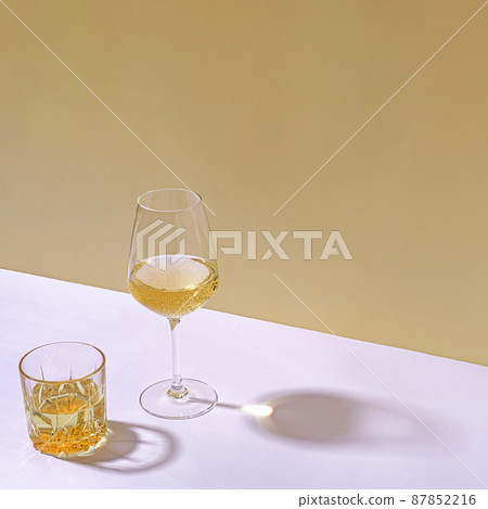 Tumbler of whiskey and glass of white wine 87852216