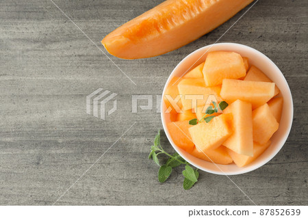 Bowl with melon pieces on gray textured table Bowl with melon pieces on gray textured table 87852639