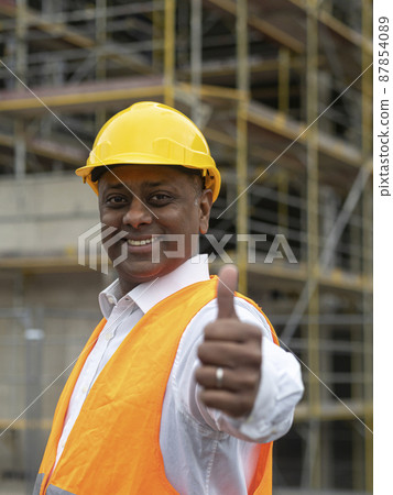 Positive, smiling and successful Indian construction worker posing looking at the camera and showing a thumbs up gesture 87854089