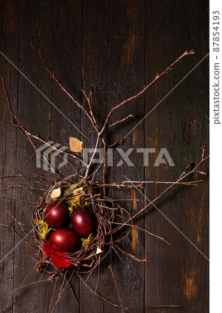 Beautiful burgundy eggs in a nest on wooden background Beautiful burgundy eggs in a nest on wooden background 87854193