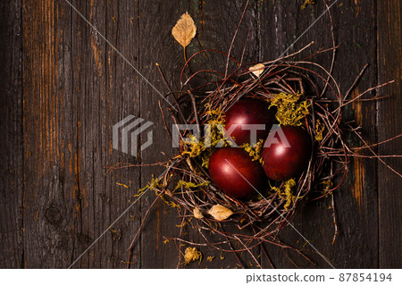 burgundy eggs in a nest on wooden background burgundy eggs in a nest on wooden background 87854194