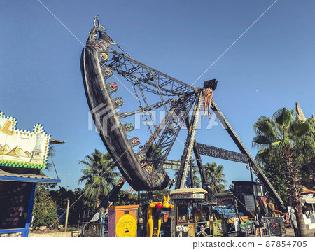 a huge carousel in the shape of a boat. entertainment for lovers of extreme recreation. ride on a dangerous carousel, pirate ship attraction a huge carousel in the shape of a boat. entertainment for lovers of extreme recreation. ride on a dangerous carousel, pirate ship attraction 87854705