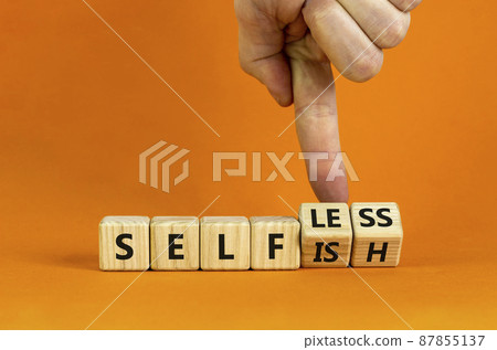 Selfish or selfless symbol. Businessman turns cubes and changes the word 'selfish' to 'selfless'. Beautiful orange background, copy space. Business, psuchological and selfish or selfless concept. Selfish or selfless symbol. Businessman turns cubes and changes the word 'selfish' to 'selfless'. Beautiful orange background, copy space. Business, psuchological and selfish or selfless concept. 87855137