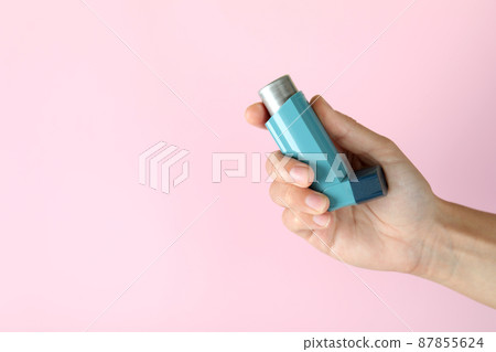 Female hand holds asthma inhaler on pink background Female hand holds asthma inhaler on pink background 87855624
