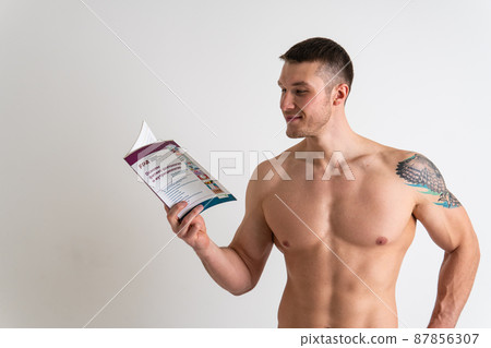 Bodybuilder reads the book on a white background isolated at the bottom of his head on his hands bodybuilder book muscular, muscle glasses bodybuilding chest shirtless, happy fit. ABS strength tan Bodybuilder reads the book on a white background isolated at the bottom of his head on his hands bodybuilder book muscular, muscle glasses bodybuilding chest shirtless, happy fit. ABS strength tan 87856307