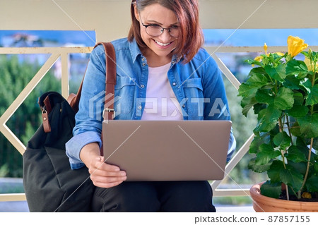 Positive smiling middle-aged business woman with laptop outdoors. Positive smiling middle-aged business woman with laptop outdoors. 87857155