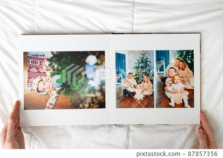 hands with book with new year photos of big family at home on a white background hands with book with new year photos of big family at home on a white background 87857356