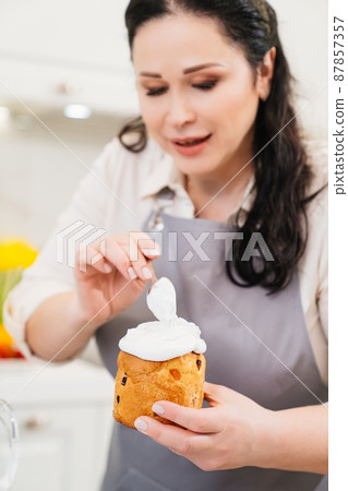 a woman cook decorates icing, fondant or marshmallow easter cakes. a woman cook decorates icing, fondant or marshmallow easter cakes. 87857357