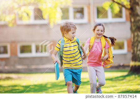 Boy and girl running to the school Boy and girl running to the school 87857414