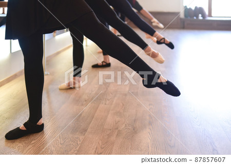 low section of The graceful legs of ballet dancers standing in a row perform stretching exercises low section of The graceful legs of ballet dancers standing in a row perform stretching exercises 87857607