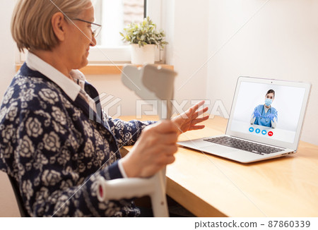 Retired senior elderly woman talking to GP female doctor via virtual telemedicine video call 87860339