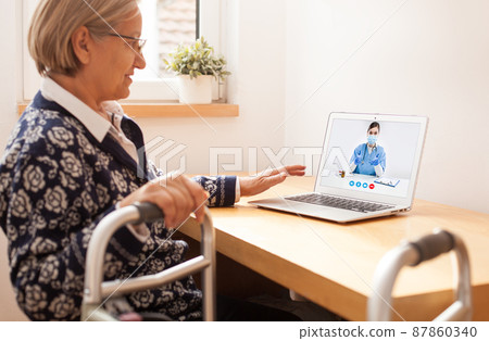Retired senior elderly woman with mobility problem talking to UK NHS GP female doctor via virtual telemedicine video call Retired senior elderly woman with mobility problem talking to UK NHS GP female doctor via virtual telemedicine video call 87860340