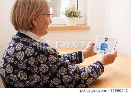 Retired senior elderly woman talking to GP physician via virtual telemedicine video call 87860342