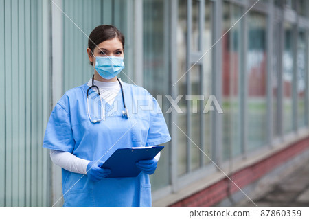 Portrait of tired exhausted female caucasian NHS key doctor in front of clinic or hospital 87860359