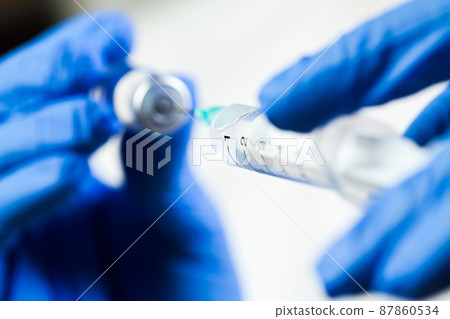 Medical syringe needle drawing vaccine shot from glass ampoule bottle 87860534